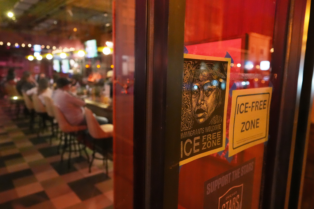 Signs saying immigrants are welcome and U.S. Immigration and Customs Enforcement agents are not, hang in the window of a sports bar in Chicago's Logan Square neighborhood, down the road from Funston Elementary School, Tuesday, Oct. 14, 2025. (AP Photo/Rebecca Blackwell)