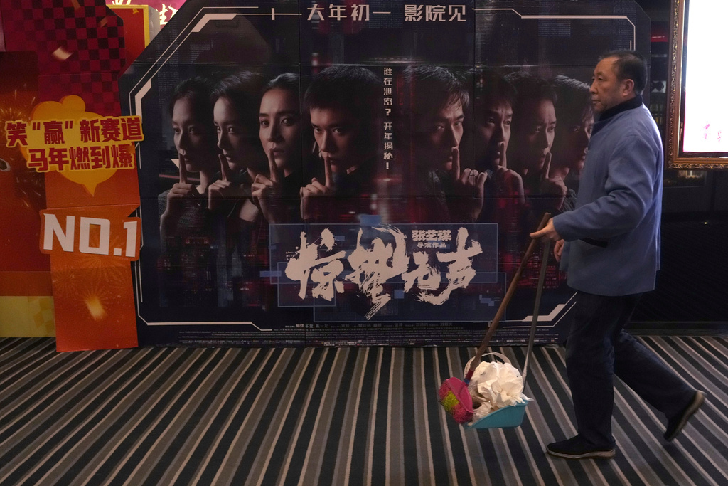 A cleaner walks past a promotion board for "Scare Out" at a cinema in Beijing, Saturday, March 7, 2026. (AP Photo/Ng Han Guan)