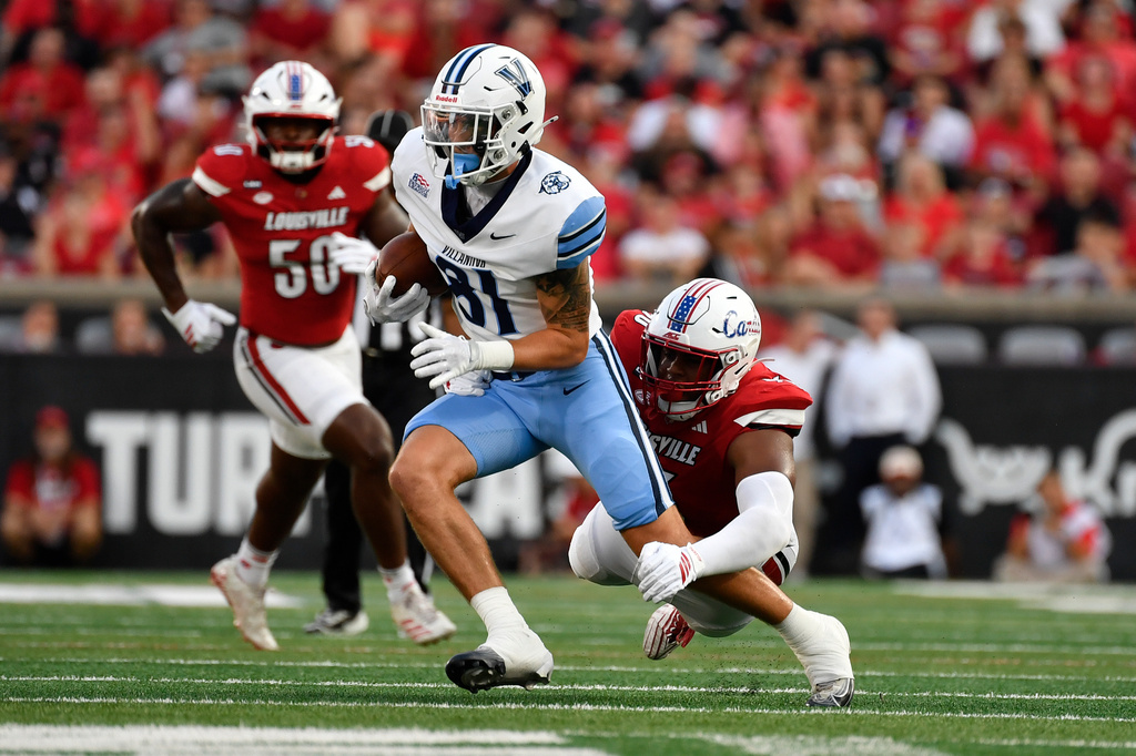 Villanova wide receiver Brandon Binkowski (81) attempts to avoid the tackle attempt by Louisville defensive lineman Tommy Ziesmer (96) during the first half of an NCAA college football game in Louisville, Ky., Friday, Sept. 11, 2026. (AP Photo/Timothy D. Easley)