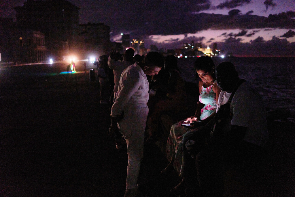 People spend the night in the dark on the Malecon during a blackout in Havana, Cuba, Saturday, March 21, 2026. (AP Photo/Ramon Espinosa)