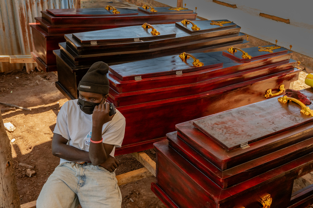 Djakisa Christian, 18, a funeral home manager, sits in front of coffins for sale at his shop in Bunia, Congo, Friday, May 22, 2026. (AP Photo/Moses Sawasawa)