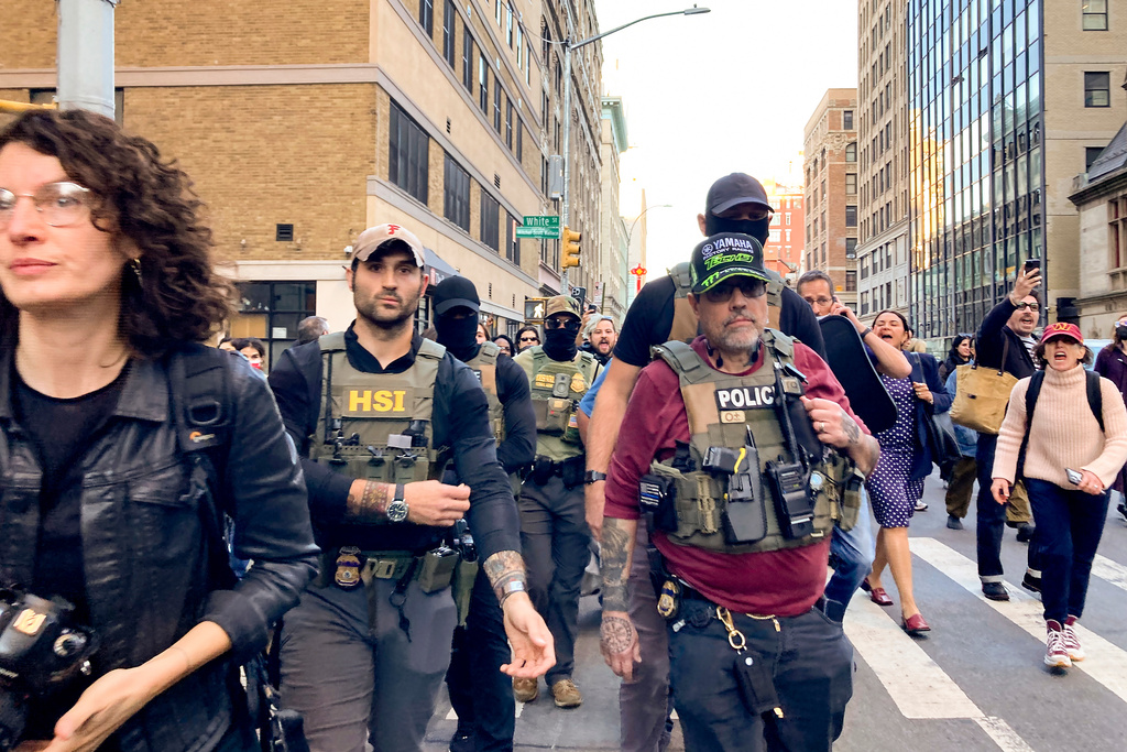 Federal agents walk down Lafayette Street as demonstrators follow behind after an immigration sweep on Canal Street through Chinatown, Tuesday, Oct. 21, 2025, in New York. (AP Photo/Jake Offenhartz)