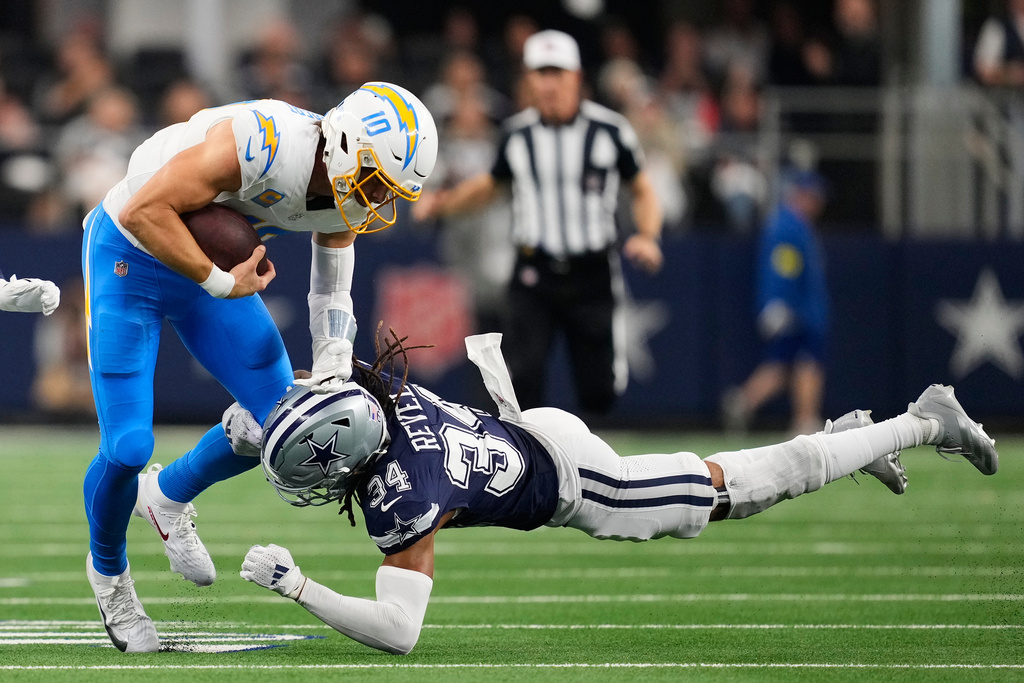 Los Angeles Chargers quarterback Justin Herbert (10) is tackled by Dallas Cowboys cornerback Shavon Revel during the second half of an NFL football game Sunday, Dec. 21, 2025, in Arlington, Texas. (AP Photo/Tony Gutierrez)