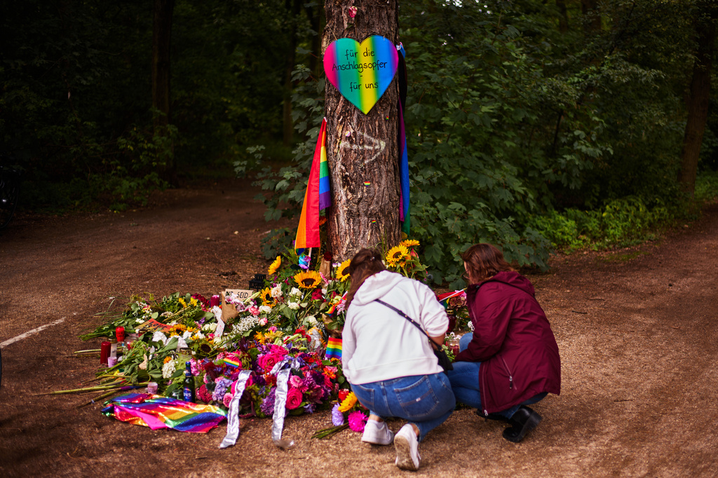 Women lay flowers at a tree in the Tiergarten Park, near the scene where a car rammed into people after Saturday's Pride March in Berlin, Germany, Monday, July 27, 2026. (AP Photo/Markus Schreiber)