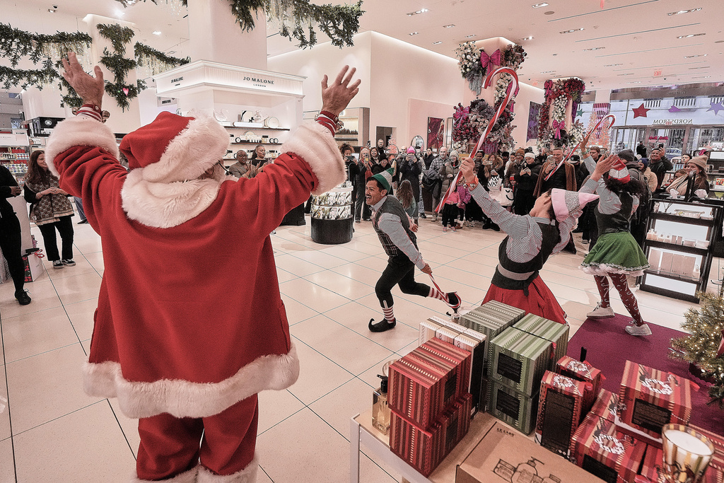 People portraying Santa and his elves perform in the cosmetics department at a Nordstrom department store, in New York, Monday, Dec. 8, 2025. (AP Photo/Richard Drew)