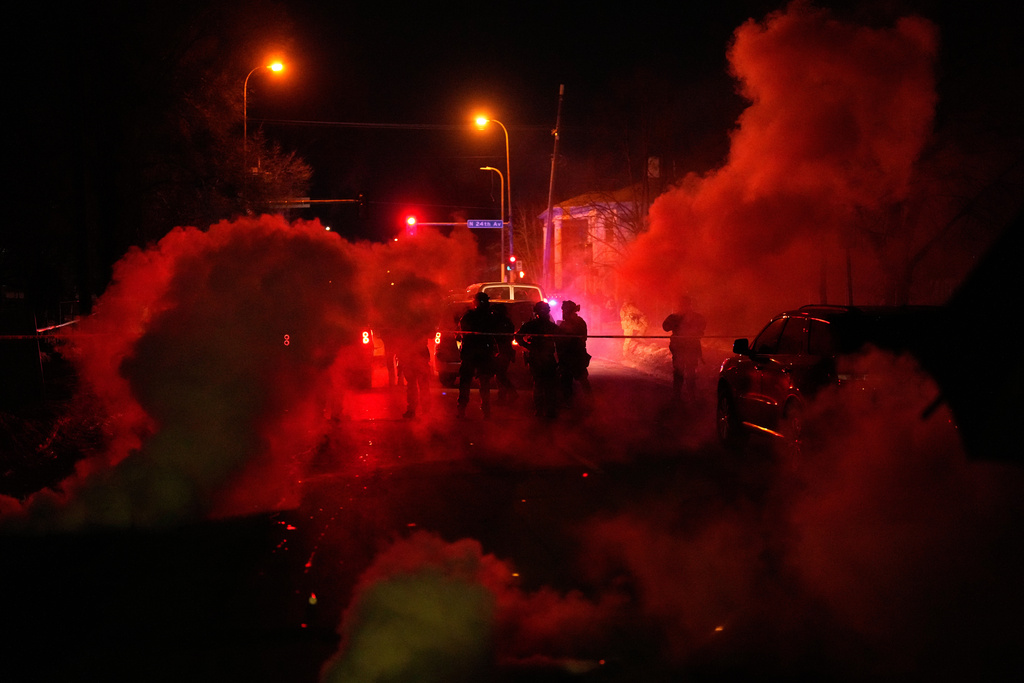 Tear gas surrounds federal law enforcement officers as they leave a scene after a shooting on Wednesday, Jan. 14, 2026, in Minneapolis. (AP Photo/John Locher)