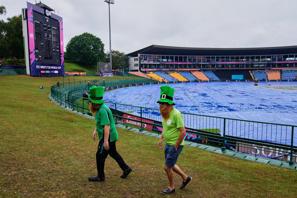 Iris fans walk by the covered ground as rain delayed the start of play during the T20 World Cup cricket match between Ireland and Zimbabwe in Pallekele, Sri Lanka, Tuesday, Feb. 17, 2026. (AP Photo/Eranga Jayawardena)