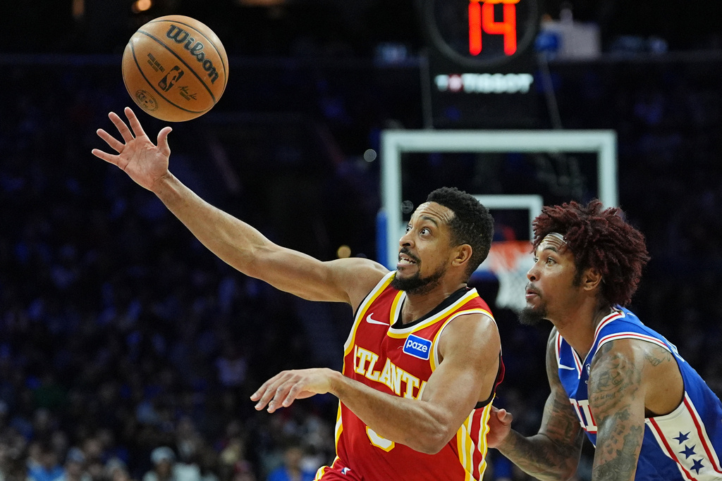 Atlanta Hawks' CJ McCollum, left, reaches for a loose ball next to Philadelphia 76ers' Kelly Oubre Jr. during the first half of an NBA basketball game Thursday, Feb. 19, 2026, in Philadelphia. (AP Photo/Matt Rourke)