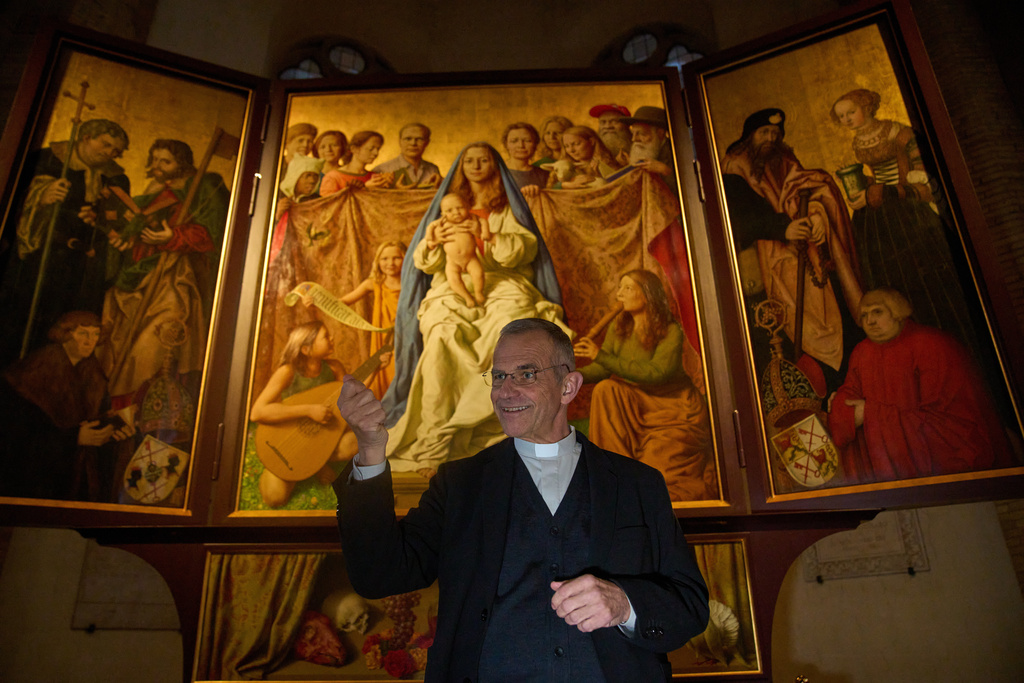 Mons. Peter Klasvogt, the rector of the Teutonic College talks during an interview with the Associated Press next to a painting exposed in the chapel of the Teutonic College by German artist Michael Triegel, who portrayed as St. Peter Burkhard Scheffler, a homeless man who died from the cold in 2022 on the edge of St. Peter's Square, at the Vatican, Wednesday, Dec. 10, 2025. (AP Photo/Alessandra Tarantino)