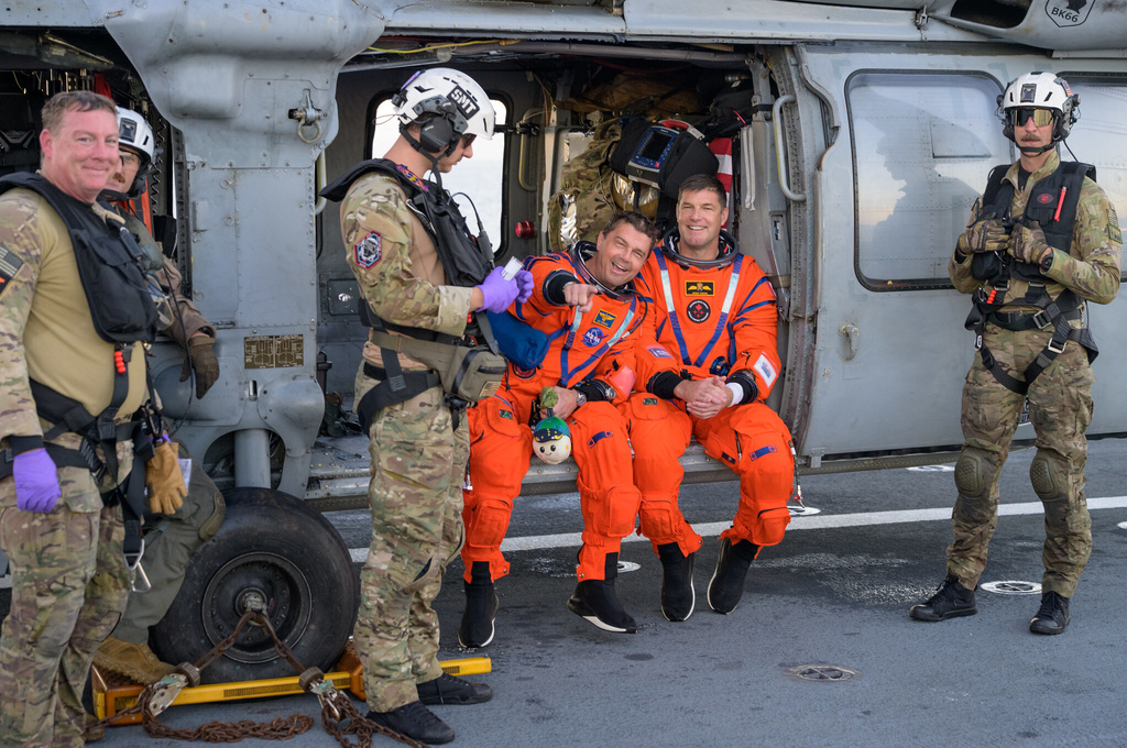 In this photo provided by NASA, The Artemis II astronauts Reid Wiseman, commander and CSA (Canadian Space Agency) astronaut Jeremy Hansen, are photographed on the flight deck of USS John P. Murtha after they were extracted from their Orion spacecraft after splashdown on Friday, April 11, 2026. (NASA via AP)