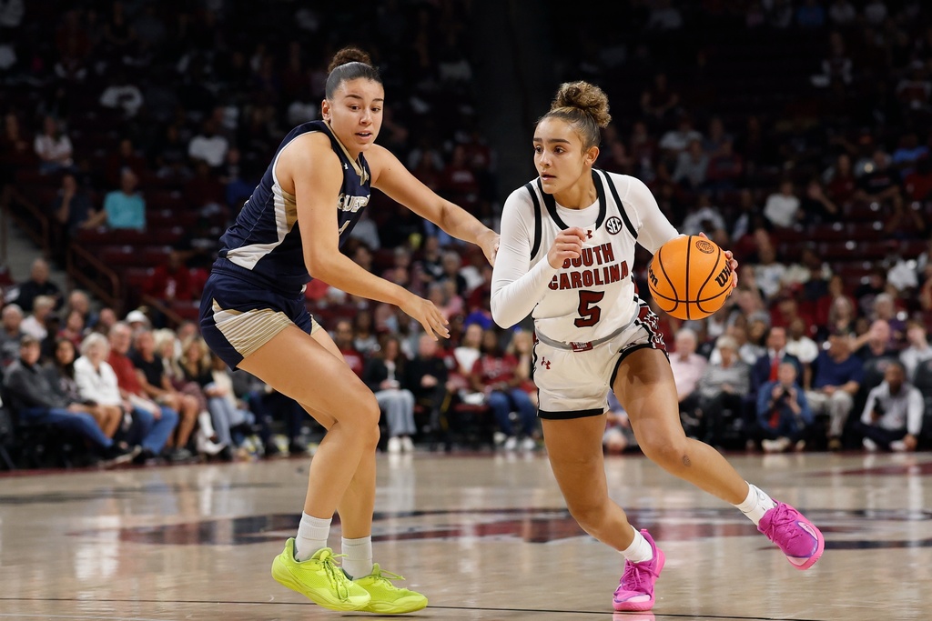 South Carolina guard Tessa Johnson (5) drives past Queens of Charlotte guard Ana Barreto, left, during the first half of an NCAA college basketball game in Columbia, S.C., Sunday, Nov. 23, 2025. (AP Photo/Nell Redmond)