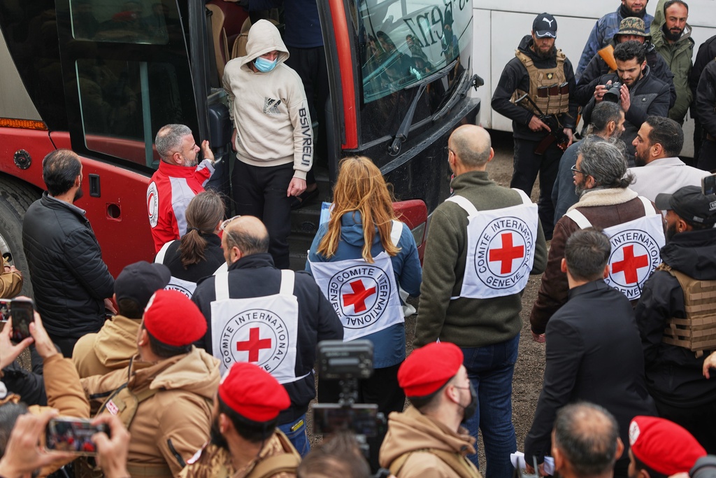 Red Cross staff look on as Syrian government prisoners arrive by bus after their release in a prisoner exchange between Syrian government forces and Druze militiamen in Sweida province, Syria, Thursday, Feb. 26, 2026. (AP Photo/Ghaith Alsayed)