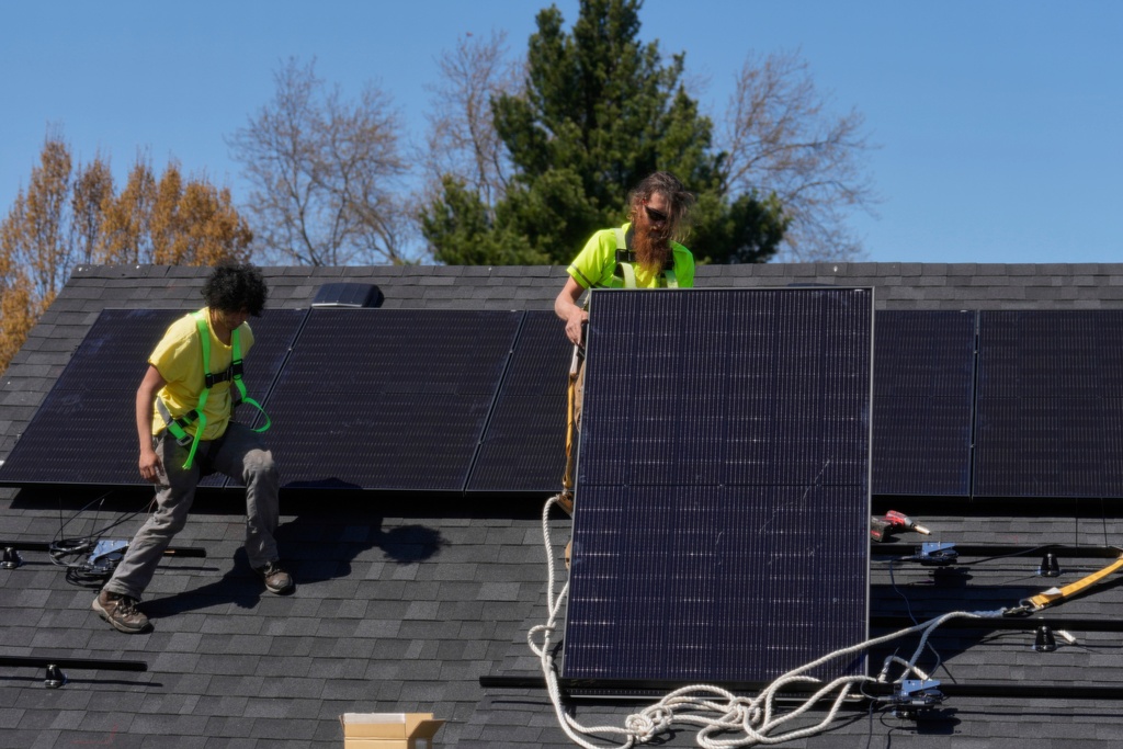 FILE - Brayan Santos, left, and Theodore Tanczuk, right, of solar installer YellowLite, put solar panels on the roof of a home in Lakewood, Ohio, April 16, 2025. (AP Photo/Sue Ogrocki, File)