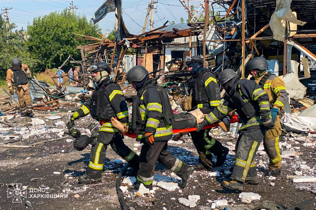 In this photo, provided by the Ukrainian Emergency Service, rescuers carry a body that they removed from under the rubble of a private house following a Russian air attack in Pechenihy, Kharkiv region, Ukraine, Tuesday, Aug. 18, 2026. (Ukrainian Emergency Service via AP)