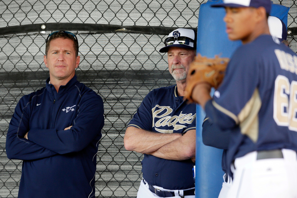 FILE - San Diego Padres executive vice president and general manager Josh Byrnes, left, and field coordinator Randy Johnson, center, watch as pitcher Joe Ross, right, throws in the bullpen during spring training baseball practice, Sunday, Feb. 16, 2014, in Peoria, Ariz. (AP Photo/Tony Gutierrez, File)