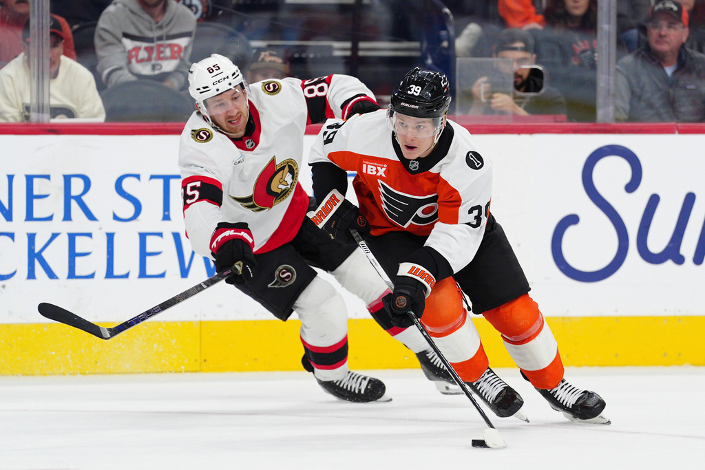 Philadelphia Flyers' Matvei Michkov, right, skates the puck past Ottawa Senators' Jake Sanderson during the second period of an NHL hockey game, Saturday, Nov. 8, 2025, in Philadelphia. (AP Photo/Derik Hamilton)