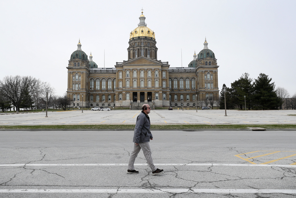 FILE - A man walks past the Iowa State Capitol building, March 26, 2020, in Des Moines, Iowa. (AP Photo/Charlie Neibergall, file)