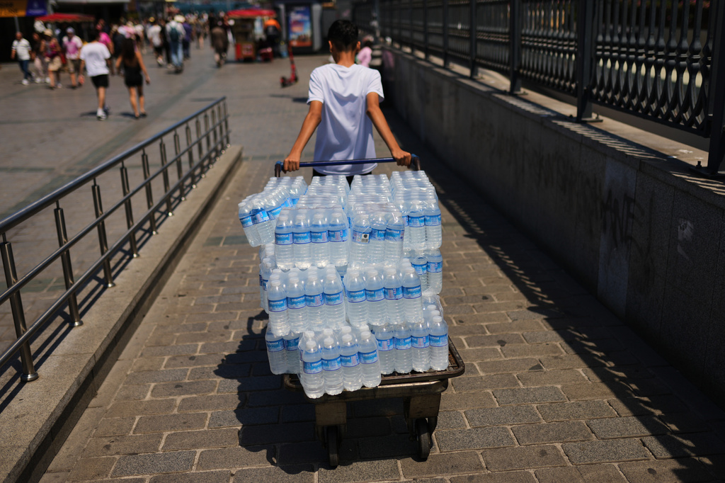 A man delivers plastic bottles of water during a hot day in Istanbul, Turkey, Saturday, June 20, 2026. (AP Photo/Francisco Seco)