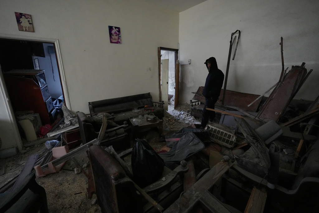 A man checks his damaged apartment at the site of a destroyed building that was hit in an Israeli airstrike in the southern port city of Tyre, Lebanon, Thursday, March 26, 2026. (AP Photo/Hussein Malla)