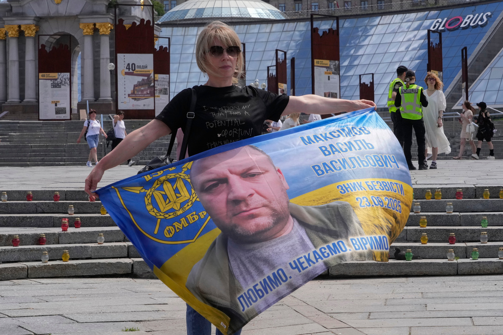A woman holds a banner with the portrait of her relative during a rally of families of missing soldiers in Kyiv, Ukraine, Friday, May 22, 2026. (AP Photo/Efrem Lukatsky)