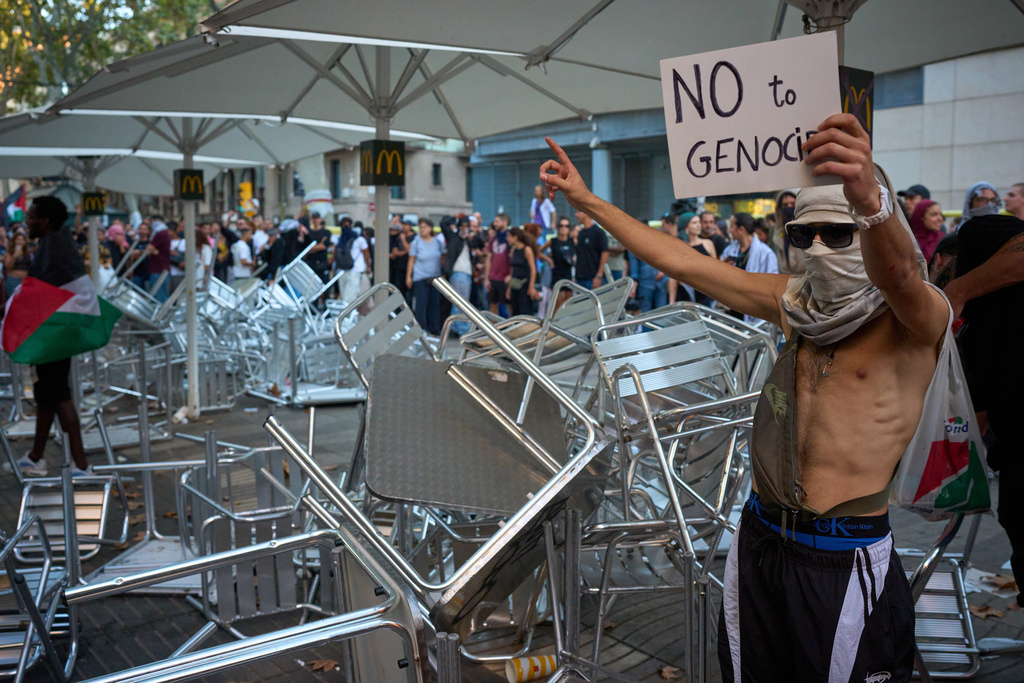 Protesters react next to a vandalized McDonald's terrace during a pro-Palestinian rally in solidarity with the Global Sumud Flotilla after ships were intercepted by the Israeli navy, in Barcelona, Spain, Saturday, Oct. 4, 2025. (AP Photo/Emilio Morenatti)