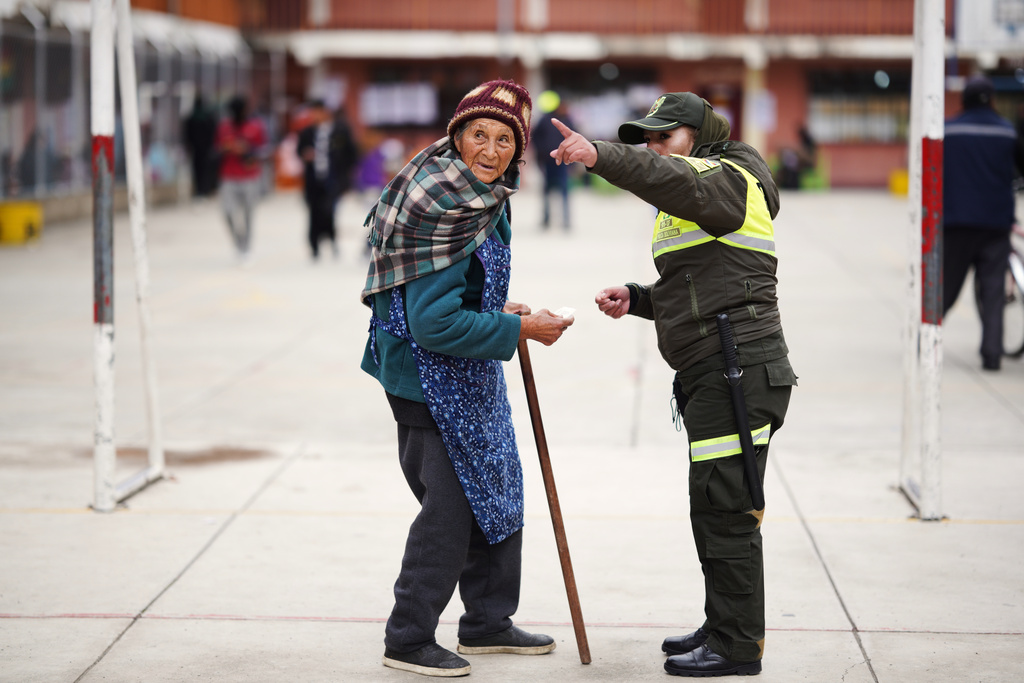 A police officer points the way to a polling station for a voter during a presidential runoff election in El Alto, Bolivia, Sunday, Oct. 19, 2025. (AP Photo/Ivan Valencia)