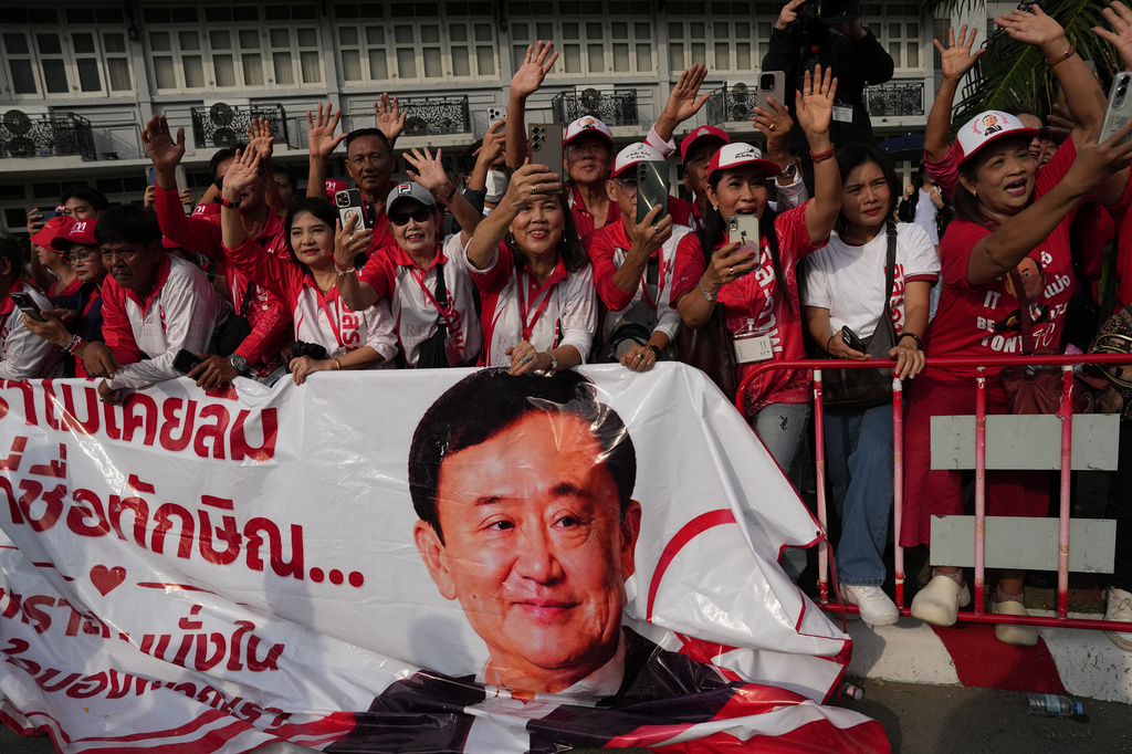 Supporters of former Thailand Prime Minister Thaksin Shinawatra wave and hold banner after he was released on parole from a Bangkok prison in Bangkok, Thailand, Monday, May 11, 2026. (AP Photo/Sakchai Lalit)