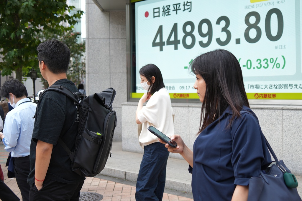 People stand in front of an electronic stock board showing Japan's Nikkei 225 index at a securities firm Tuesday, Sept. 30, 2025, in Tokyo. (AP Photo/Eugene Hoshiko)