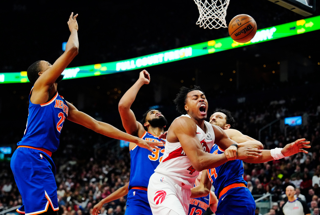 Toronto Raptors' Scottie Barnes (4) is fouled by New York Knicks' Landry Shamet (right) as Knicks' Mikal Bridges (left) and Karl-Anthony Towns (32) defend during first half NBA basketball action in Toronto on Wednesday, Jan. 28, 2026. (Frank Gunn/The Canadian Press via AP)