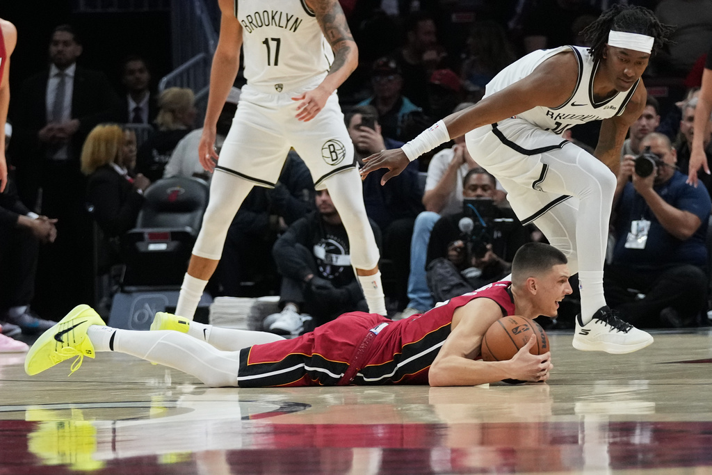 Miami Heat guard Tyler Herro falls to the court as Brooklyn Nets guard Terance Mann, right, defends during the first half of an NBA basketball game, Thursday, March 5, 2026, in Miami. (AP Photo/Lynne Sladky)