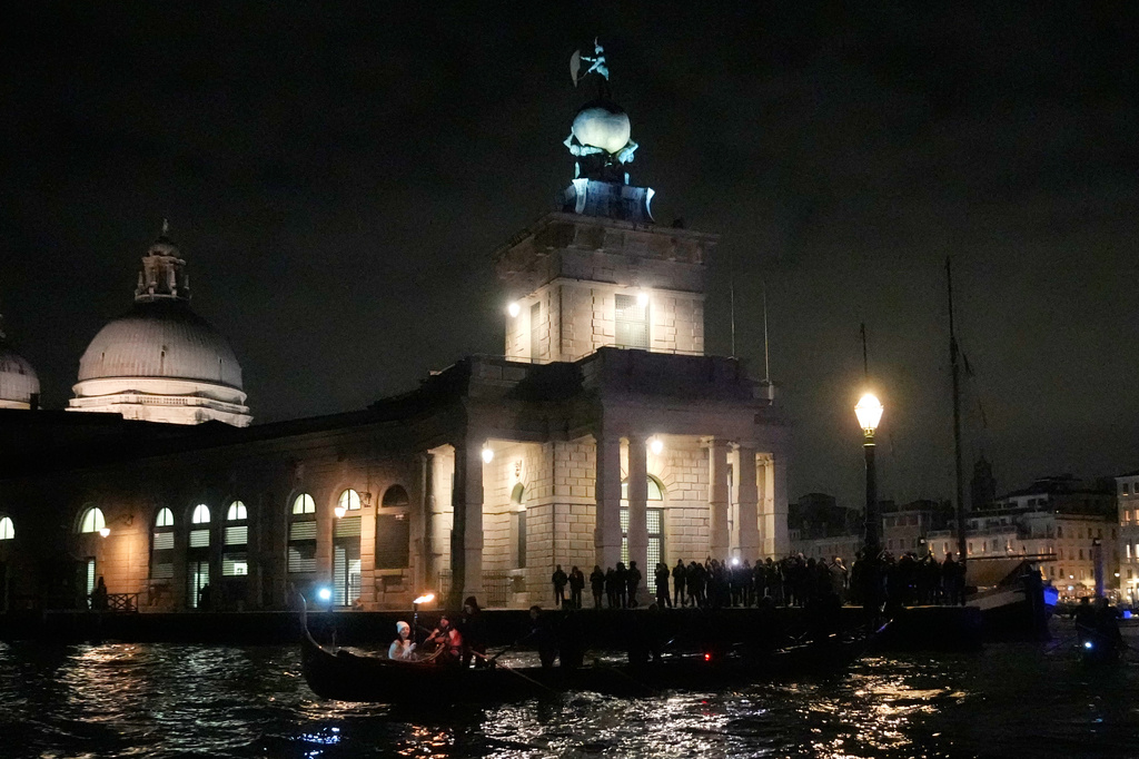 A torchbearer holds an Olympic torch flame on the Grand Canal in Venice, Italy, Thursday, Jan. 22, 2026, its journey will conclude in Milan on February 6 for the Winter Olympics opening ceremony. (AP Photo/Luca Bruno)
