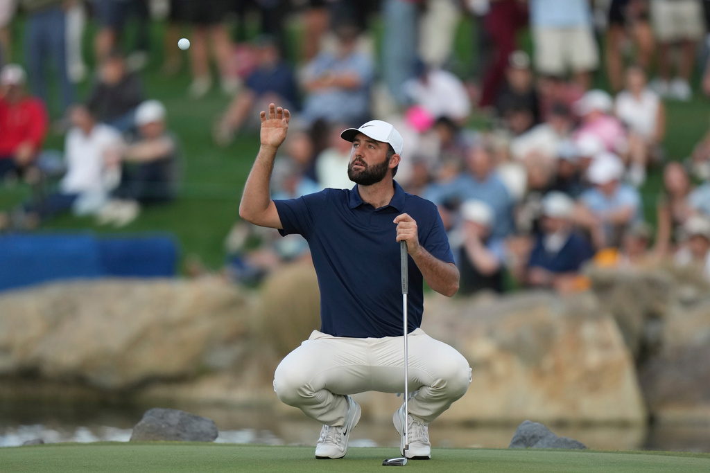 Scottie Scheffler reaches up to catch his golf ball his caddie tossed to him at the 18th green during the third round of the American Express golf event on the Pete Dye Stadium Course at PGA West Saturday, Jan. 24, 2026, in La Quinta, Calif. (AP Photo/Ross D. Franklin)
