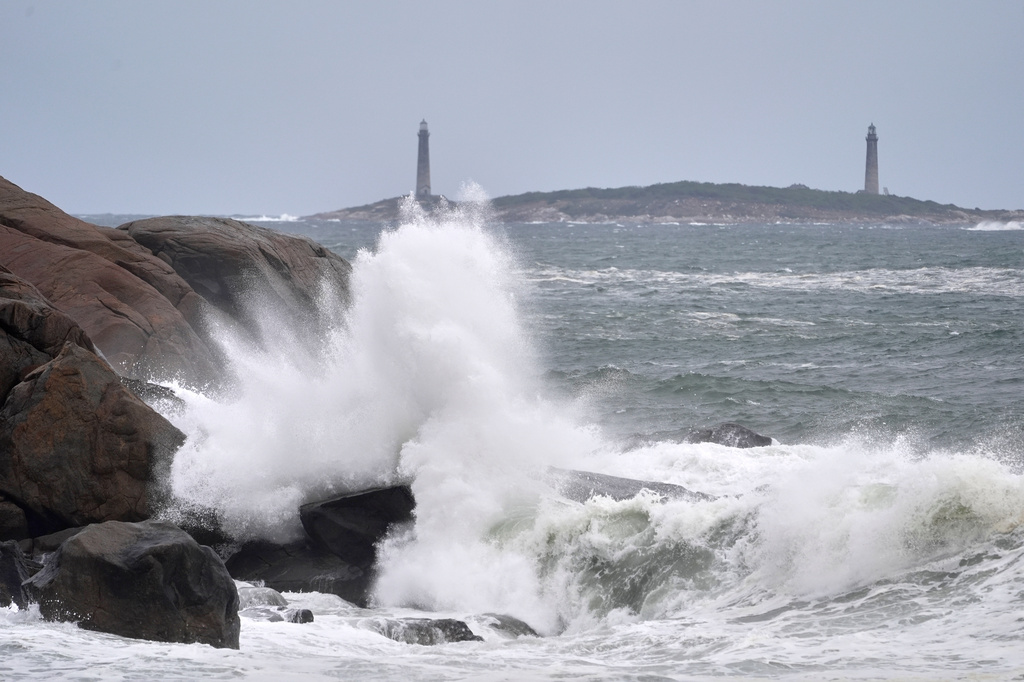 Surf breaks along the rocky coastline, with the twin lighthouses of Thatcher Island visible in the distance, during the early stages of a nor’easter Friday, Sept. 25, 2026, in Gloucester, Mass. (AP Photo/Robert F. Bukaty)