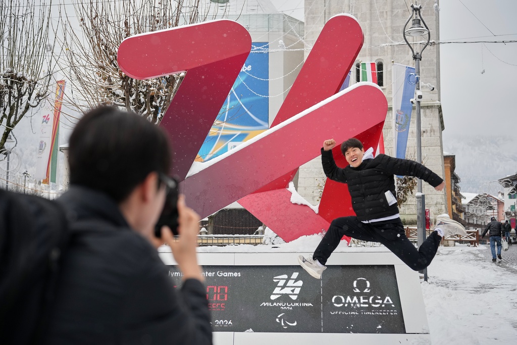 South Korean skeleton athlete Jung Seunggi, right, has a photo taken in front of the Milan Cortina Winter Olympics countdown clock, in Cortina D'Ampezzo, Thursday, Nov. 20, 2025. (AP Photo/Andrew Medichini)