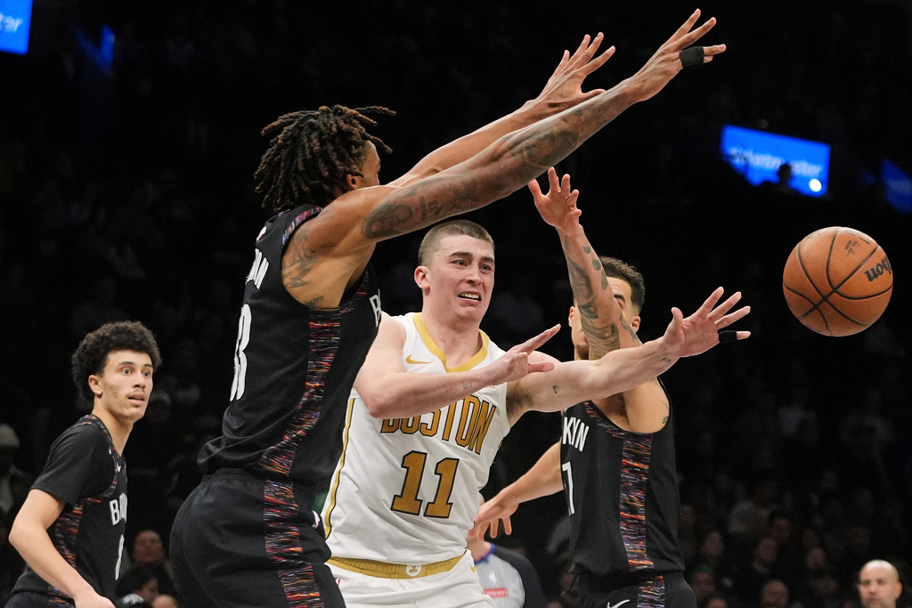 Boston Celtics' Payton Pritchard (11) passes away from Brooklyn Nets' Nic Claxton (33) and Michael Porter Jr. (17) during the second overtime of an NBA basketball game Friday, Jan. 23, 2026, in New York. (AP Photo/Frank Franklin II)
