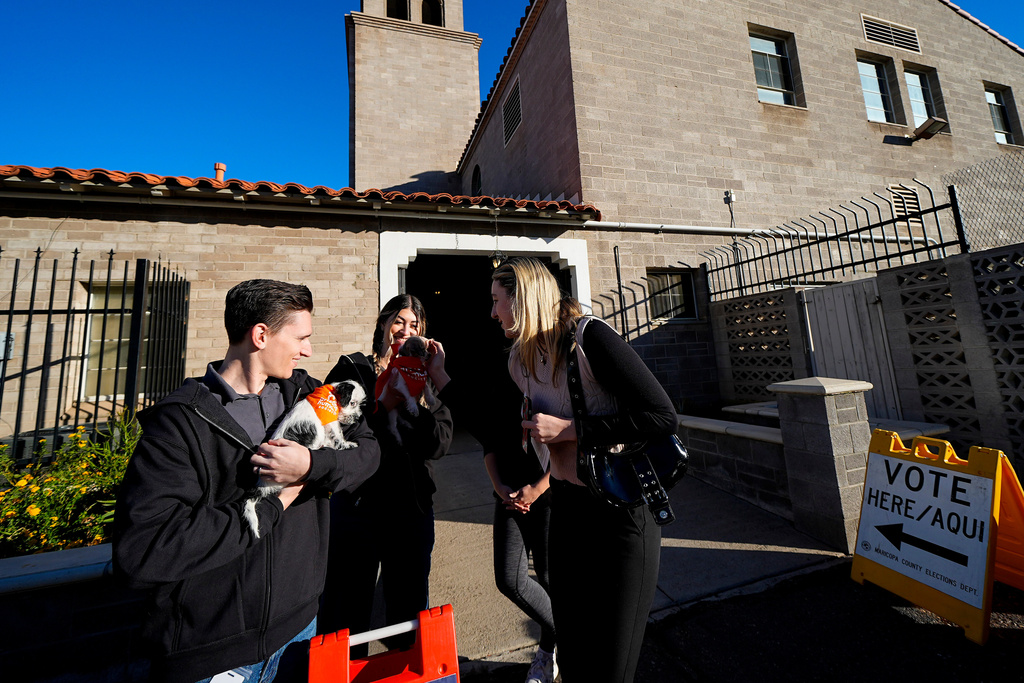 FILE - Joe Casados, left, holds a dog named Daphne, and Samantha Sasso, holds Carly, as they show the dogs to voters outside the Faith Lutheran Church to ease voter anxiety, Tuesday, Nov. 5, 2024, in Phoenix, Ariz. (AP Photo/Julio Cortez, File)