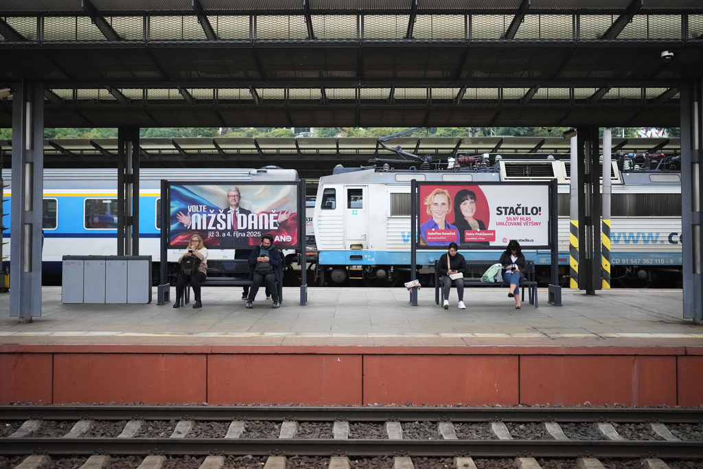 People sit by election posters ahead of Parliamentary elections in Prague, Czech Republic, Sept. 26, 2025. (AP Photo/Petr David Josek)