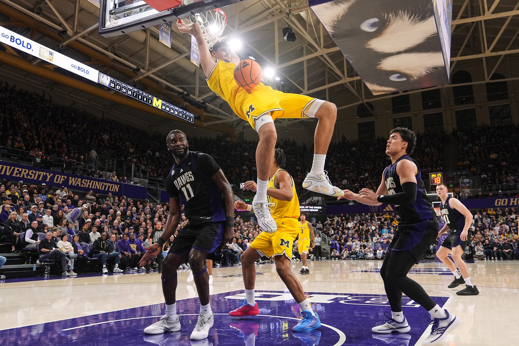 Michigan center Aday Mara dunks as Washington center Franck Kepnang (11) and guard JJ Mandaquit, right, look on during the second half of an NCAA college basketball game Wednesday, Jan. 14, 2026, in Seattle. (AP Photo/Lindsey Wasson)