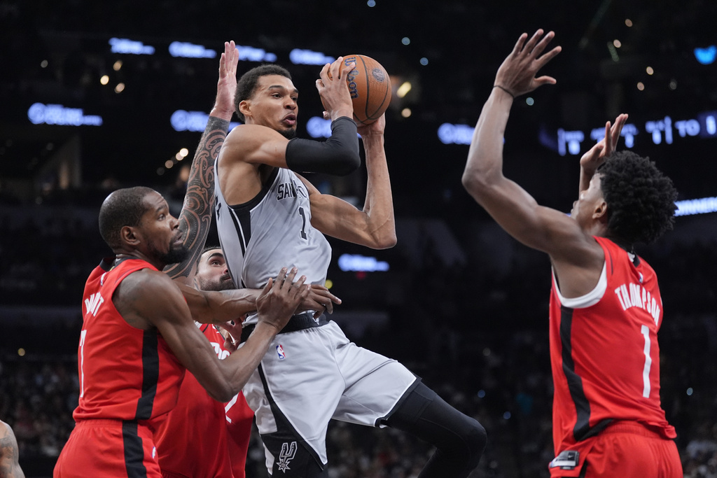 San Antonio Spurs forward Victor Wembanyama, center, is pressured by Houston Rockets forward Kevin Durant (7), center Steven Adams (12) and guard Amen Thompson, right, during the first half of an NBA Cup basketball game in San Antonio, Friday, Nov. 7, 2025. (AP Photo/Eric Gay)