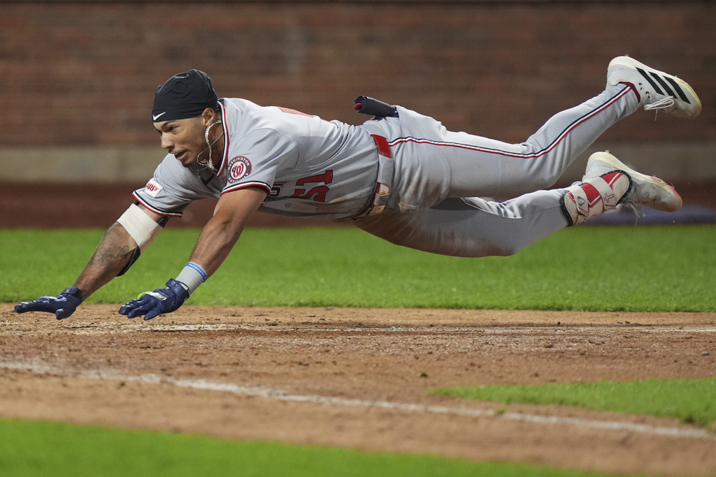 Washington Nationals' Daylen Lile dives to home plate to score on a two-run inside-the-park home run during the 11th inning of a baseball game against the New York Mets Saturday, Sept. 20, 2025, in New York. (AP Photo/Frank Franklin II)