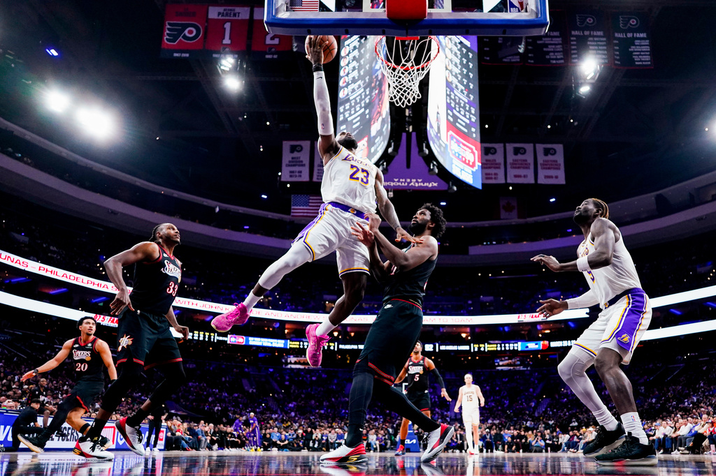 FILE - Los Angeles Lakers' LeBron James, center left, goes up for the shot against Philadelphia 76ers' Joel Embiid, center right, during the second half of an NBA basketball game, Dec. 7, 2025, in Philadelphia. (AP Photo/Chris Szagola, File)