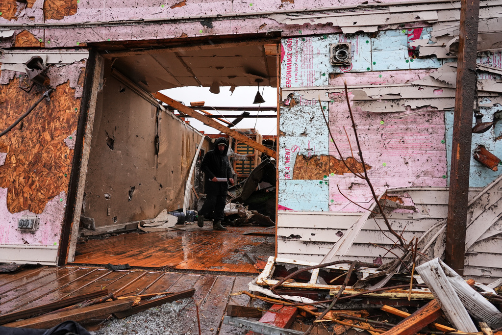 Josh Johnson searches through his belongings at a damaged home in the aftermath of a powerful storm that ripped through the area a day earlier, in Aroma Park, Ill., Wednesday, March 11, 2026. (AP Photo/Nam Y. Huh)
