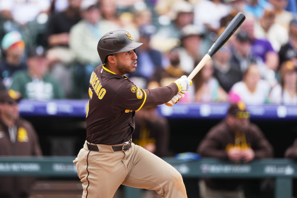 San Diego Padres' Ramón Laureano follows the flight of his triple off Colorado Rockies relief pitcher Zach Agnos in the fourth inning of a baseball game Thursday, April 23, 2026, in Denver. (AP Photo/David Zalubowski)