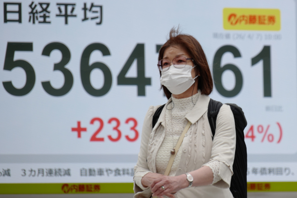 A person walks in front of an electronic stock board showing Japan's Nikkei index at a securities firm Tuesday, April 7, 2026, in Tokyo. (AP Photo/Eugene Hoshiko)