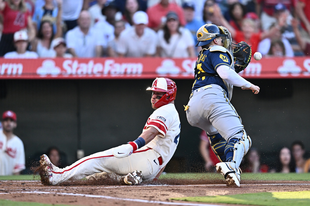 Los Angeles Angels' Mike Trout, left, slides to score during the first inning of a baseball game against the Milwaukee Brewers, Saturday, Aug. 1, 2026, in Anaheim, Calif. (AP Photo/William Liang)
