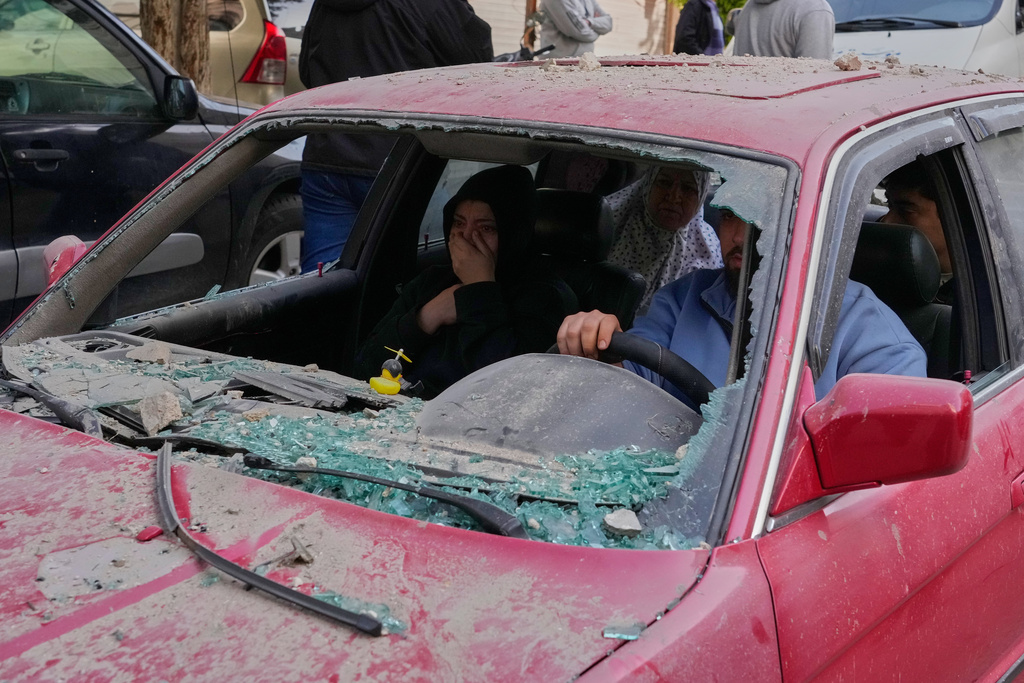 Family members ride in a damaged car, as they flee the site of an Israeli airstrike that hit an apartment building in the southern port city of Sidon, Lebanon, Friday, March 13, 2026. (AP Photo/Mohammed Zaatari)