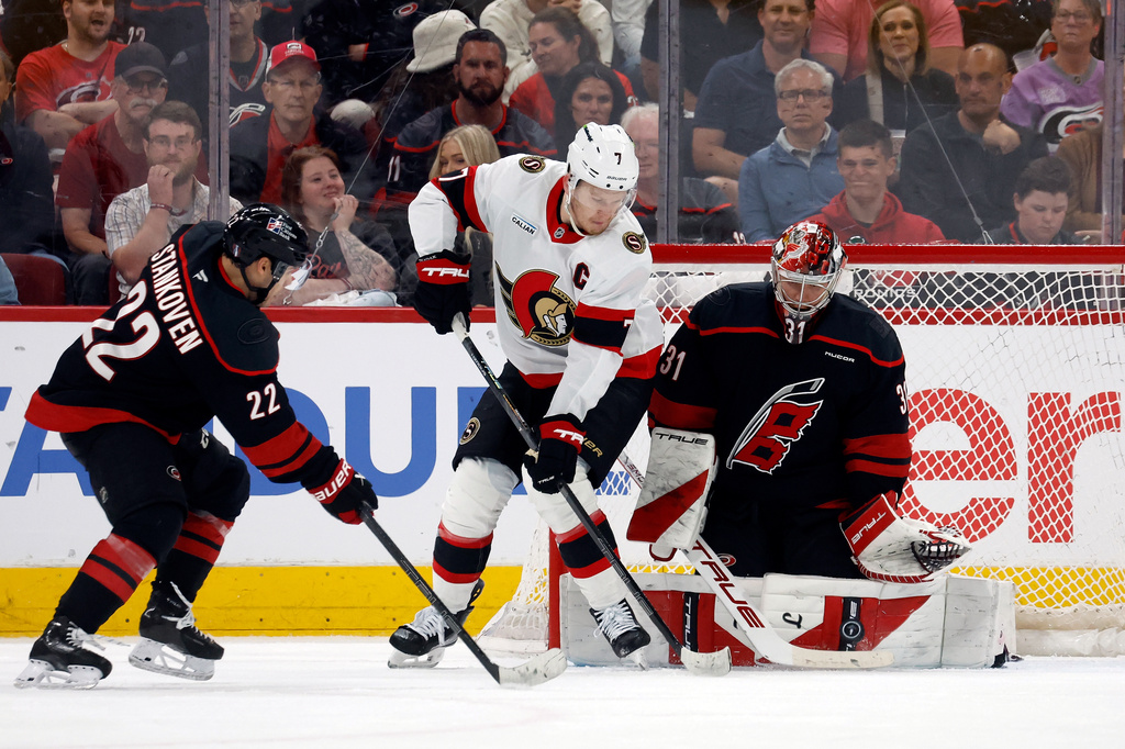 Carolina Hurricanes goaltender Frederik Andersen (31) blocks a shot by Ottawa Senators' Brady Tkachuk (7) with Hurricanes' Logan Stankoven (22) nearby during the second period of an Game 1 of an NHL hockey Stanley Cup first-round playoff series in Raleigh, N.C., Saturday, April 18, 2026. (AP Photo/Karl DeBlaker)