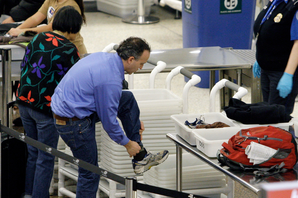 FILE - An airline passenger pulls off his shoes to be scanned as he prepares to go through a security checkpoint at Seattle-Tacoma International Airport, Jan. 4, 2010, in SeaTac, Wash. (AP Photo/Elaine Thompson, File)