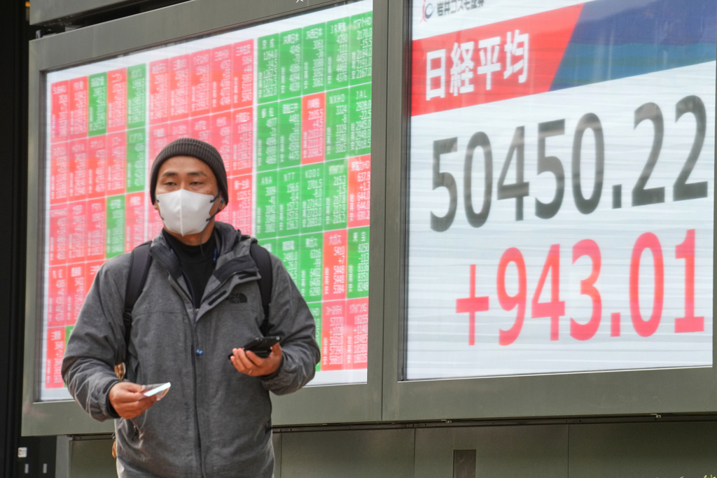 A person walks in front of an electronic stock board showing Japan's Nikkei index at a securities firm Monday, Dec. 22, 2025, in Tokyo. (AP Photo/Eugene Hoshiko)