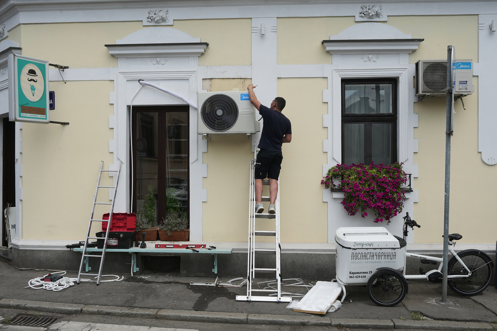 FILE - An worker installs a new air conditioning unit during a hot summer day in Belgrade, Serbia, June 30, 2026. (AP Photo/Darko Vojinovic, File)